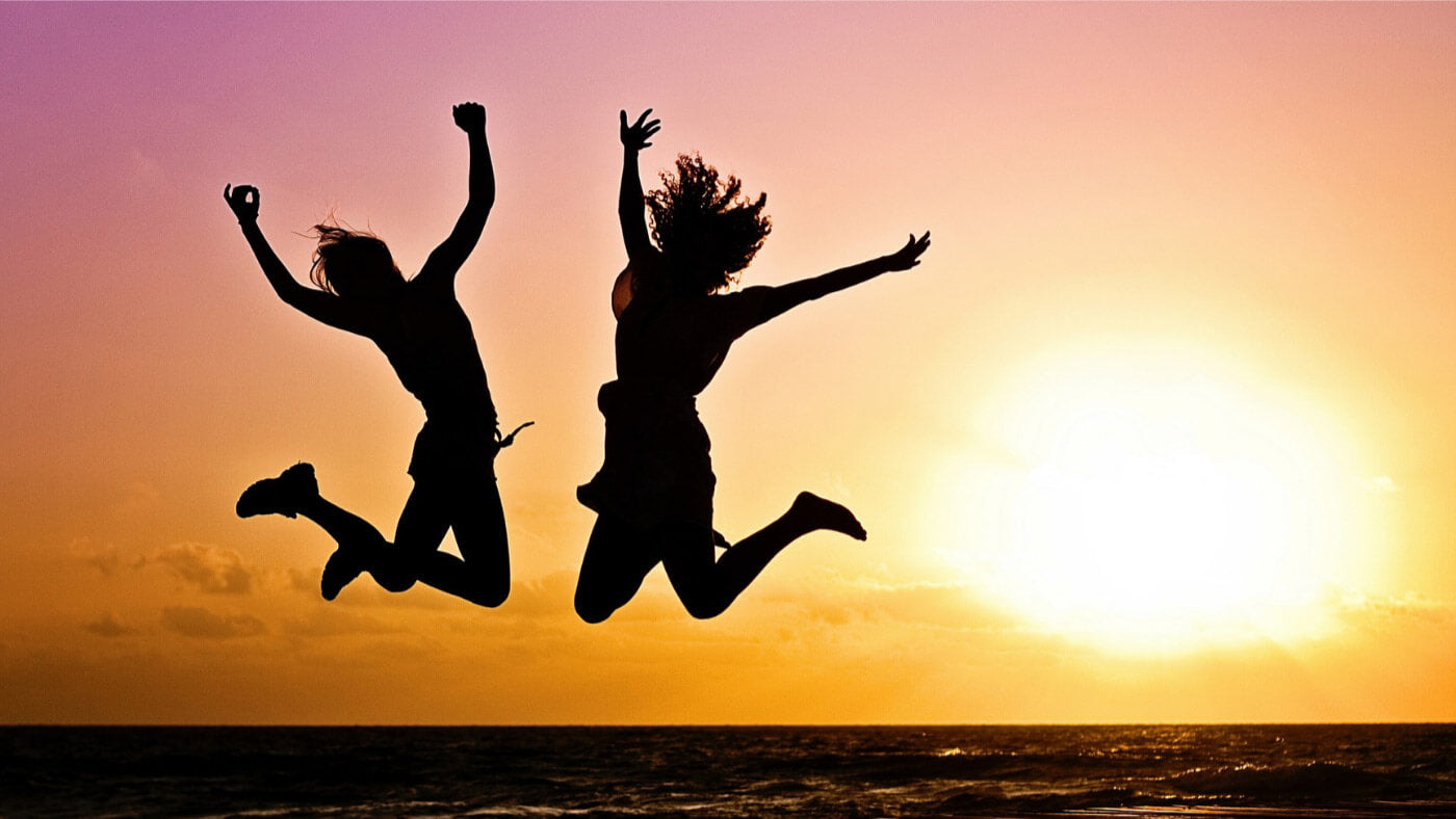 Two women jumping of joy in the sunset