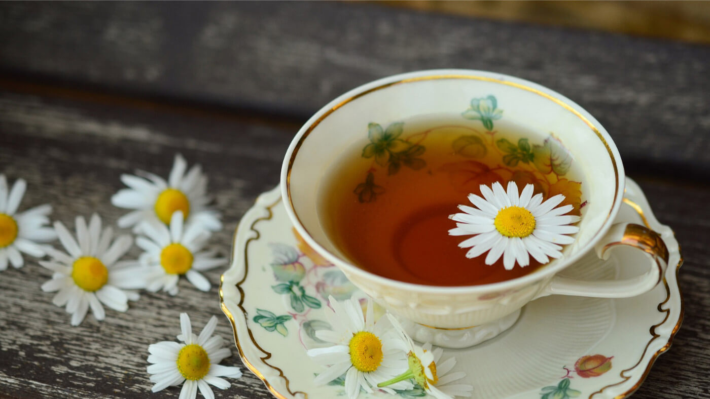 Tea cup with herbal tea and chamomile flowers