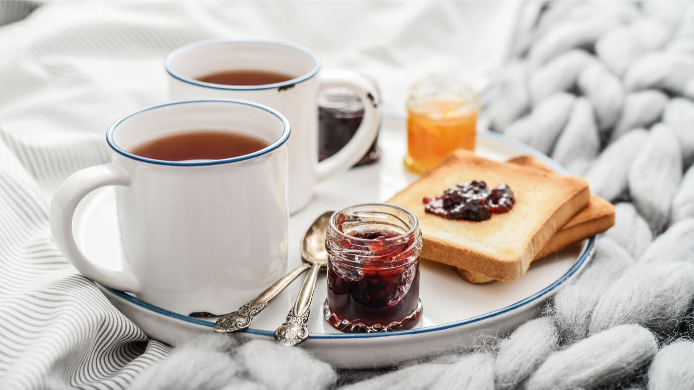 Tea cups and jam spread on bread