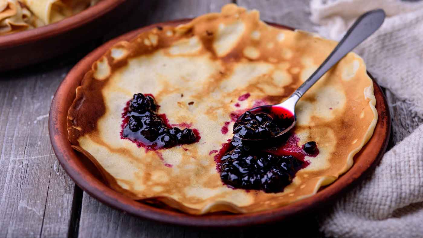 Tablespoon of fruit jam spread on French crepes