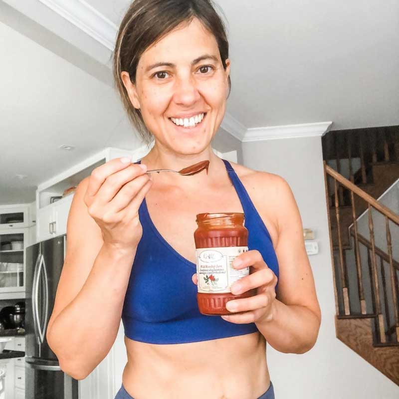 Fit woman holding a spoon and jar of Health from Europe rosehip jam